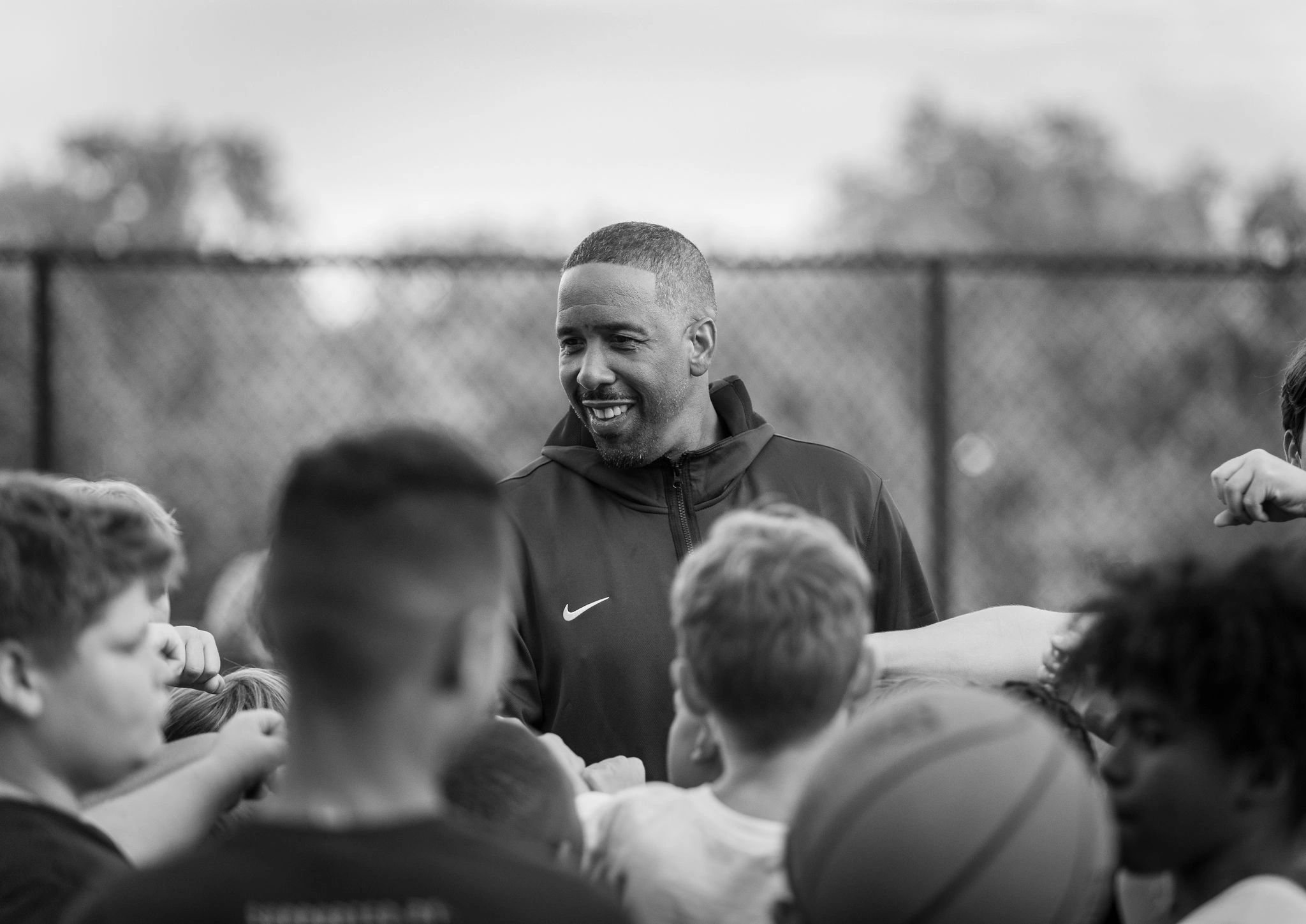 Coach smiling with kids in a group huddle.