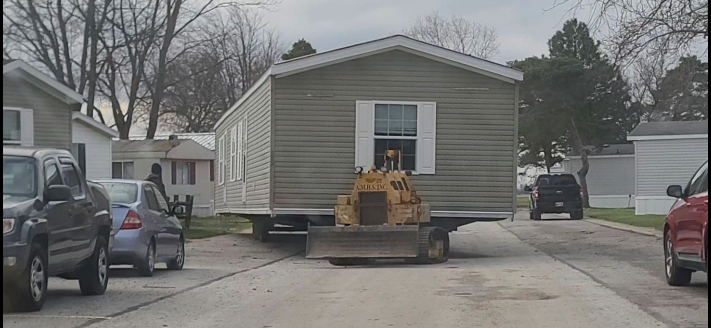 A large mobile home being moved down a street.
