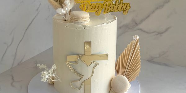 Elegant white cake with cross and dove decorations for a religious celebration.
