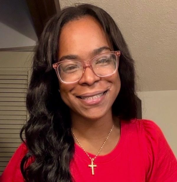 Smiling woman with glasses and cross necklace.