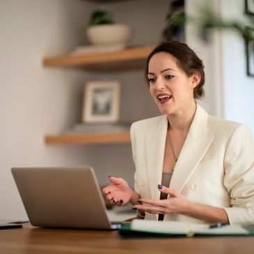 Woman video chatting on laptop at home office.