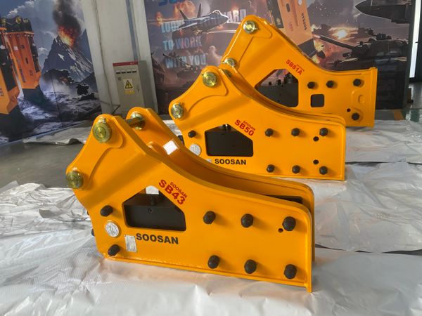 Soosan SIDE hydraulic breakers (SB series) rest on protective wrapping in a facility.