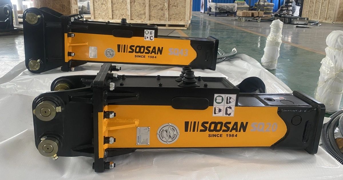 Two yellow and black Soosan hydraulic breakers placed indoors on a plastic sheet.