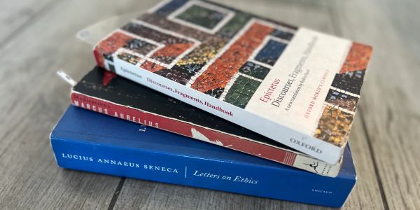 Stack of philosophy books on a wooden surface.