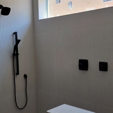 Modern minimalist shower area with black fixtures.