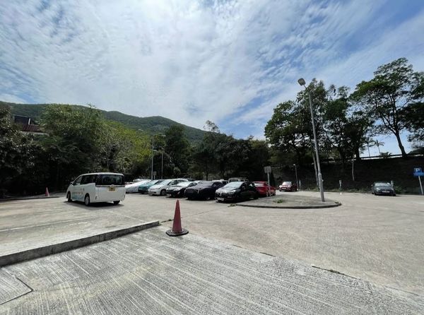 A small parking lot with several cars under a partly cloudy sky.