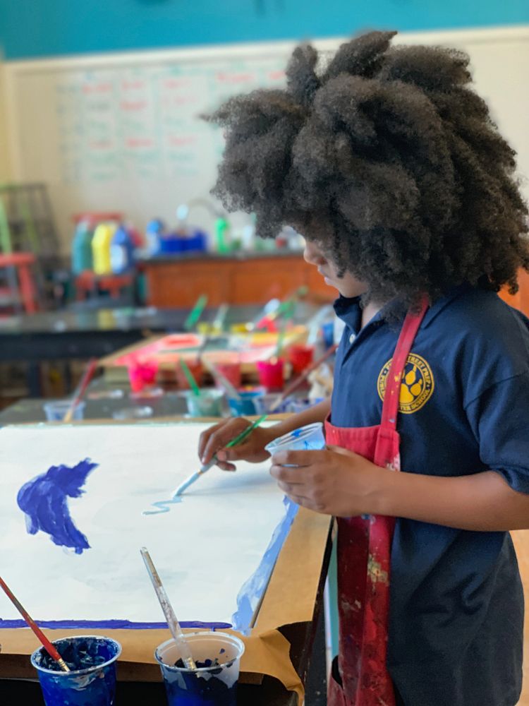 Child painting with blue colors in an art classroom.