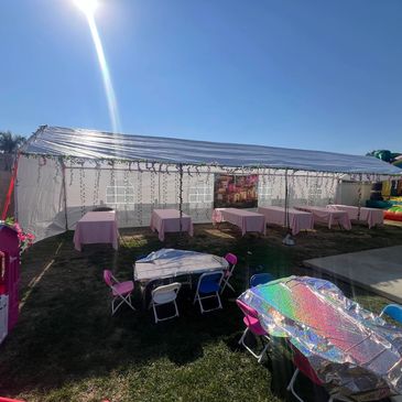 Outdoor event setup with tables and chairs under a clear sky.