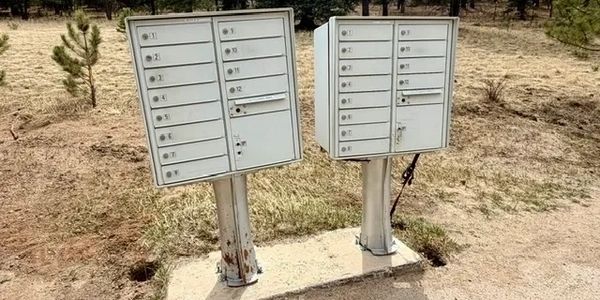 Two metal community mailbox units in a dry, rural area.