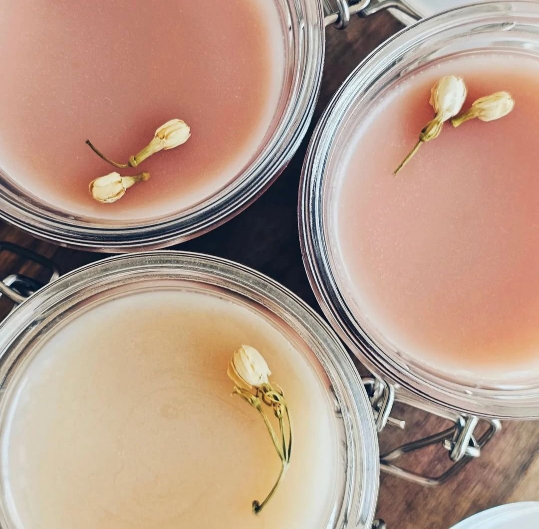 Three scented candles in glass jars with dried flower decorations.