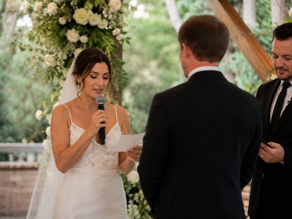 Bride reading vows during outdoor wedding ceremony.