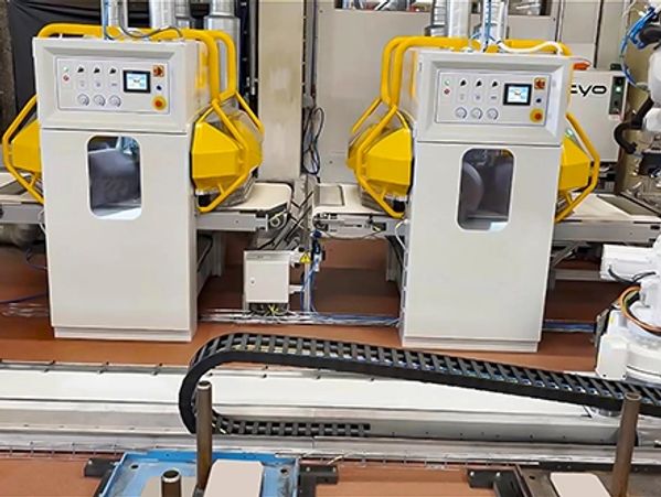 Two industrial machines with control panels and yellow safety guards in a factory setting.