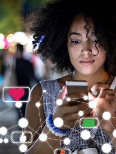 Woman using smartphone with social media icons floating around.