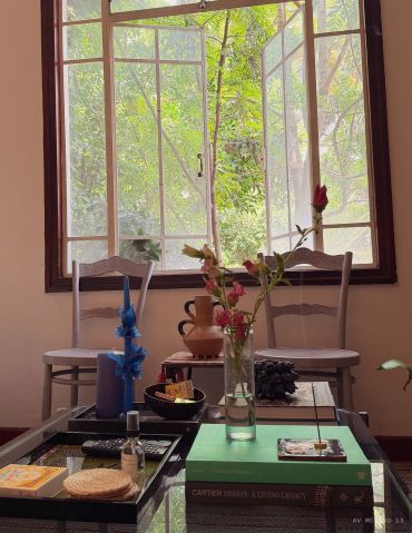 Cozy room with two chairs, a vase with flowers, and a large open window.