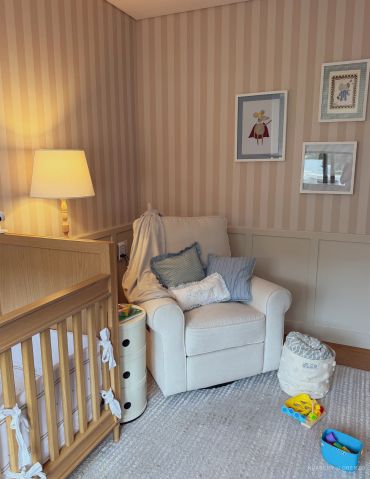 Cozy nursery corner with a white armchair, crib, and soft lighting.