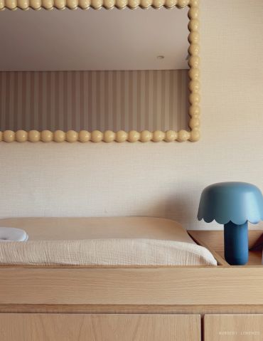 Minimalist bedroom with wooden furniture and a blue lamp.
