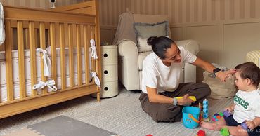 A woman playing with a baby in a cozy nursery.