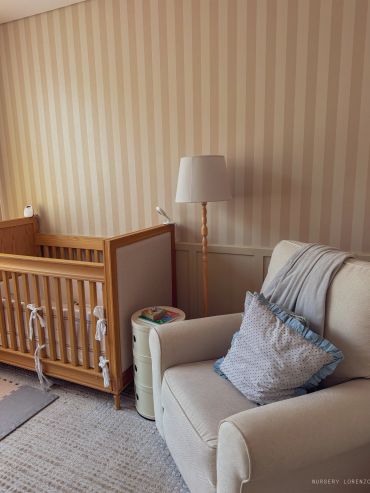 Cozy nursery corner with crib, armchair, and floor lamp.