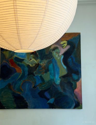 Abstract painting with dark blues and greens under a large paper lantern.