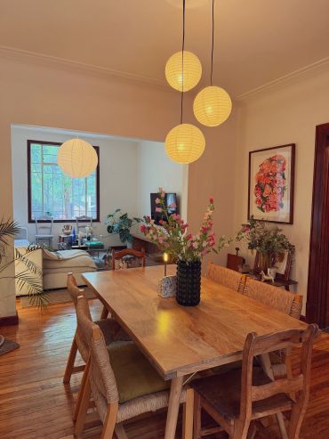 Cozy dining area with wooden table, hanging lanterns, and fresh flowers.