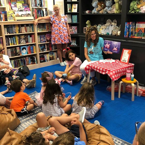 Woman reading a story to children in a bookstore's reading corner.