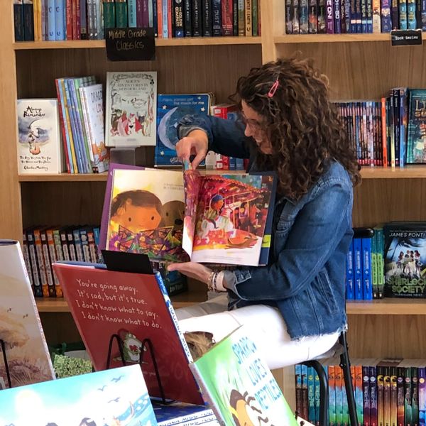 Woman reading a colorful children's book in a library.