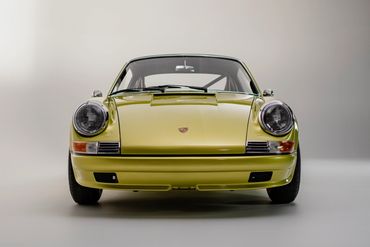 Yellow vintage Porsche sports car photographed in a studio setting.