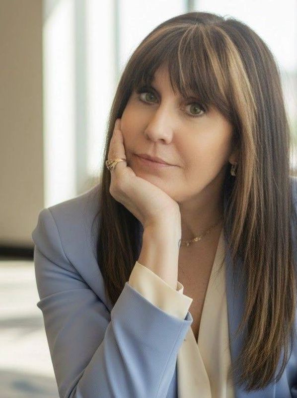 Woman with long brown hair resting her chin on hand.