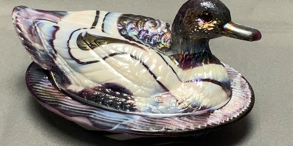Iridescent ceramic duck figurine on a neutral background.