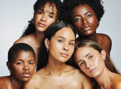 A diverse group of five women posing closely together against a plain background.