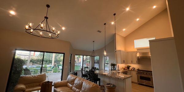 Cozy living room and kitchen with large windows and warm lighting.