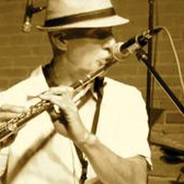 Greg playing flute into a mic in performance at the Laughing Goat Coffeehouse in Boulder, CO