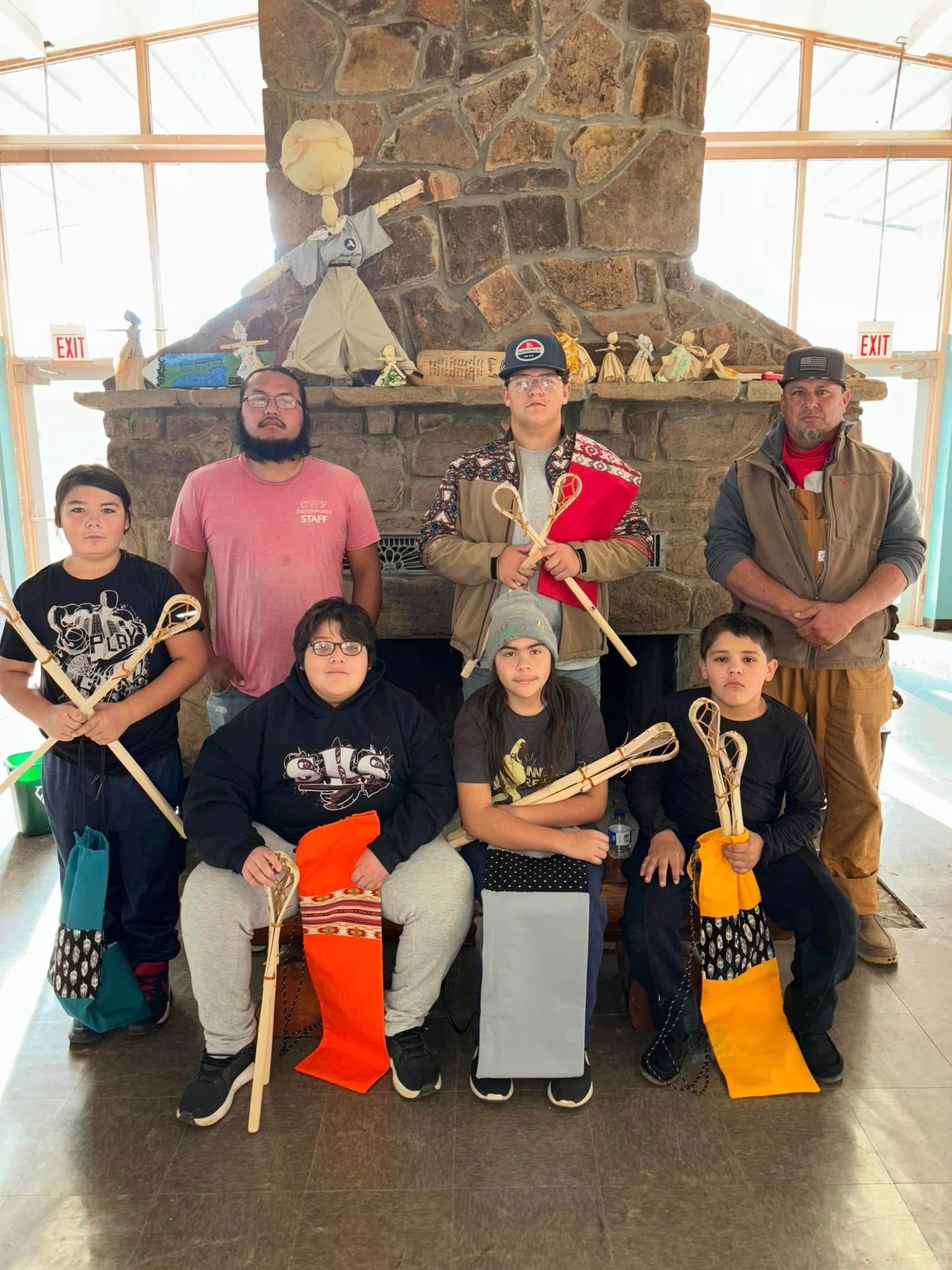 A group of Native American boys holding Stickball Sticks that they made by hand with their elder.