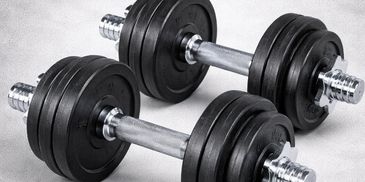 Two adjustable dumbbells with black weight plates on a gray surface.