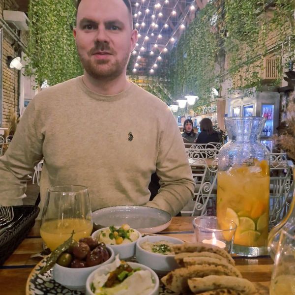 Man sitting at a restaurant table with food and drinks.