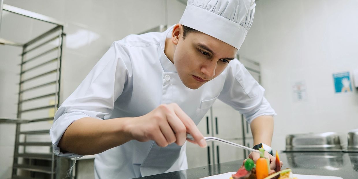 Chef carefully garnishes a dish in a professional kitchen.