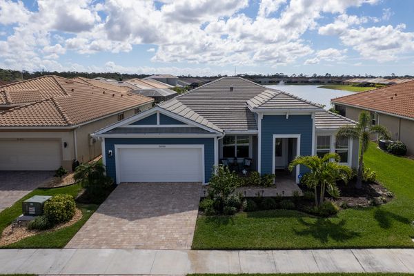 A blue single-story house with a tiled roof and lake view in the background.