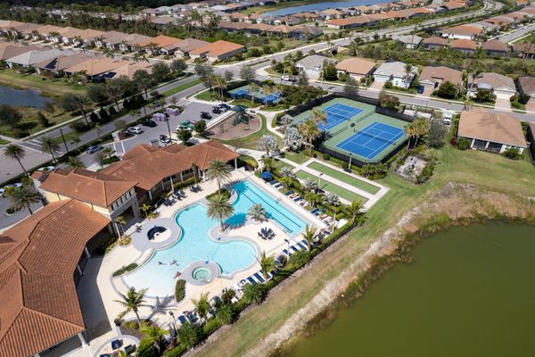 Aerial view of a residential community with a pool, tennis courts, and playground.