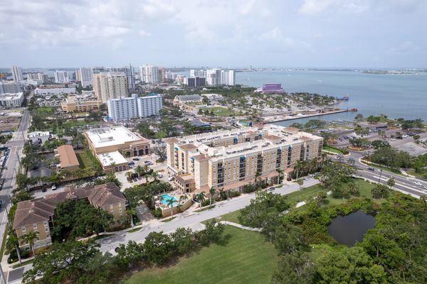 Aerial view of a coastal city with buildings, greenery, and water.
