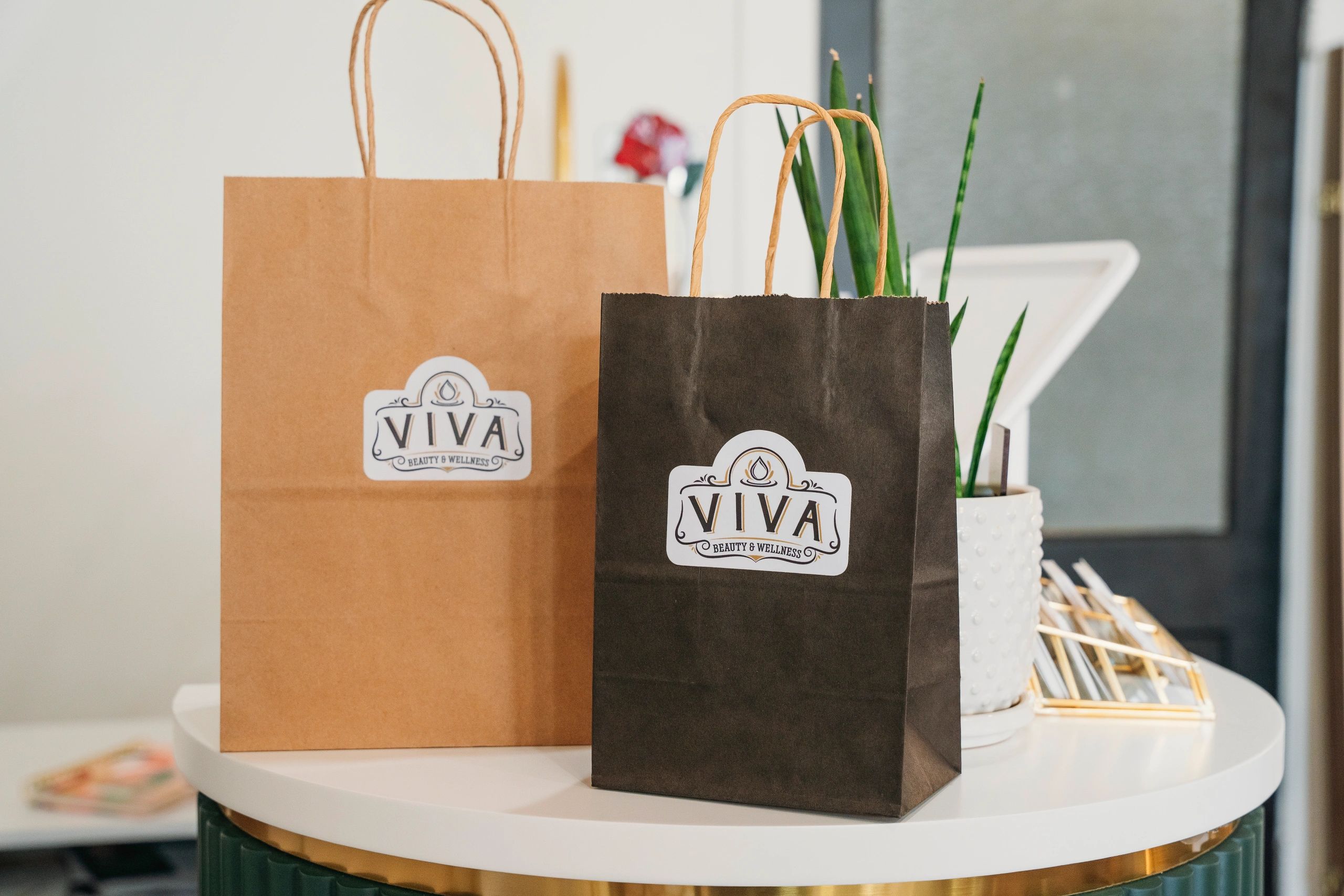 Two paper bags labeled 'Viva Beauty &amp; Wellness' on a white table.