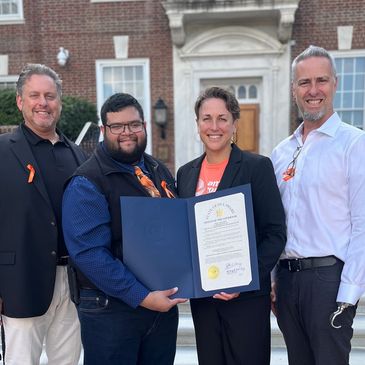 Steve Burke, Sean Samitt, Suzen DuBre, Darryl DuBre holding Delaware Proclamation for Amputee Month.