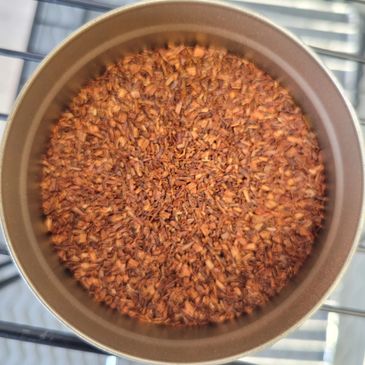 A pot filled with reddish-brown seeds or grains.
