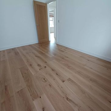 Empty room with light wood flooring and open door.
