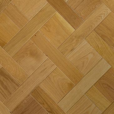 Close-up of a wooden parquet floor with a herringbone pattern.