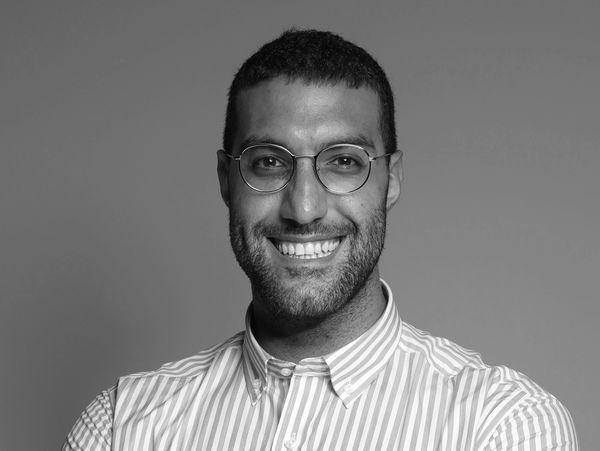 Smiling man with glasses in a striped shirt poses confidently.