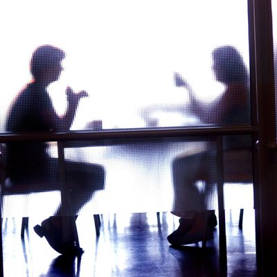Silhouetted people having a conversation behind frosted glass.