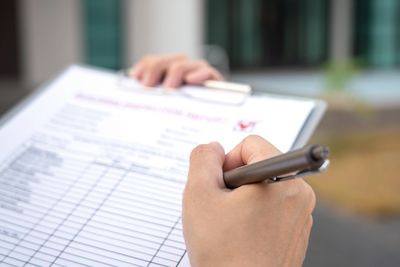 Person filling out a form on a clipboard with a pen.