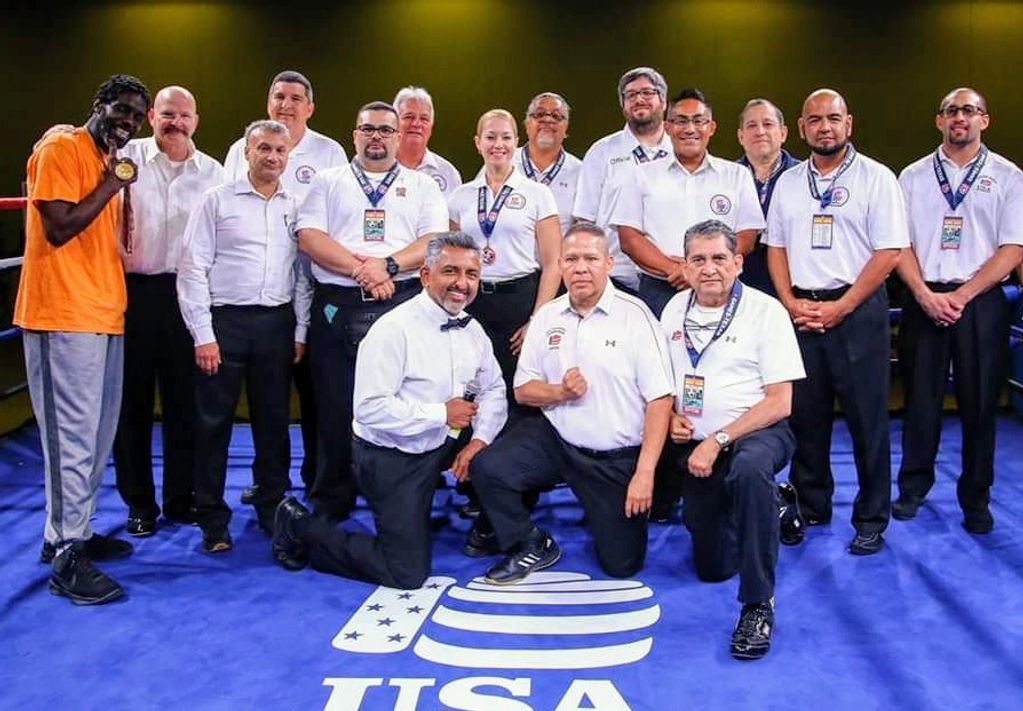 Group photo of referees and a boxer in a boxing ring with USA logo.