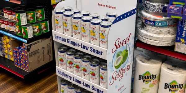 Grocery shelf with sweet seltzer cans and paper towels.