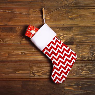 Zig zag design on holiday stocking with wrapped gift in it, hung on a line with a clothes pin